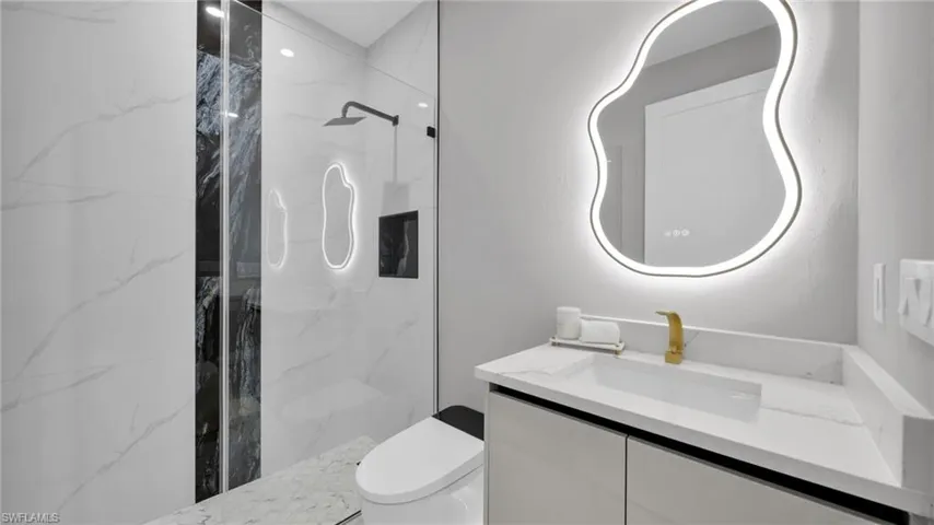 Bathroom with vanity and a marble finish shower