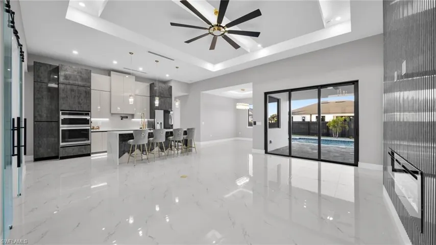 Living room featuring light marble finish floors, ceiling fan, recessed lighting, and a tray ceiling