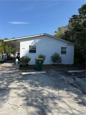 View of side of home with stucco siding and a carport