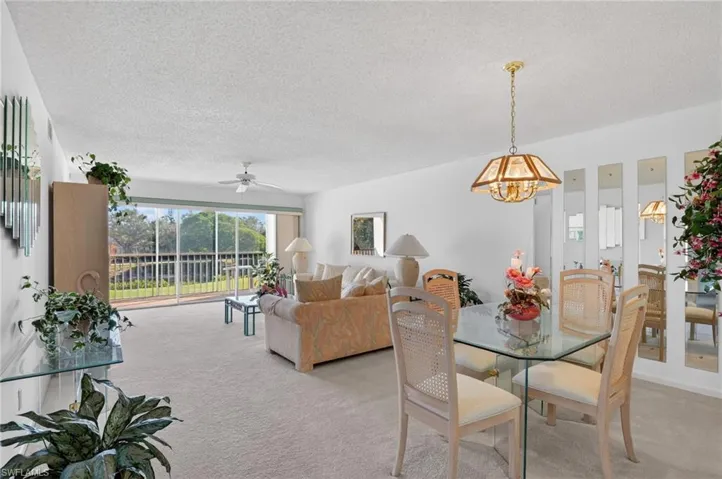 Dining space with a textured ceiling, light carpet, and a ceiling fan