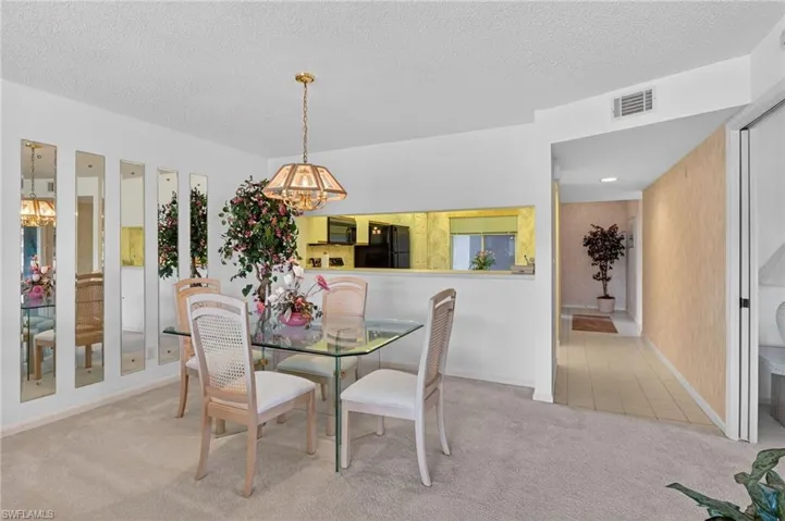 Carpeted dining area with a chandelier and a textured ceiling