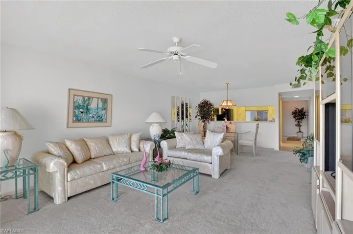 Living room with light carpet, a textured ceiling, and a ceiling fan