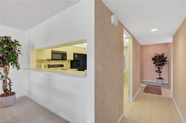 Kitchen with light countertops, black appliances, cream cabinets, recessed lighting, and backsplash