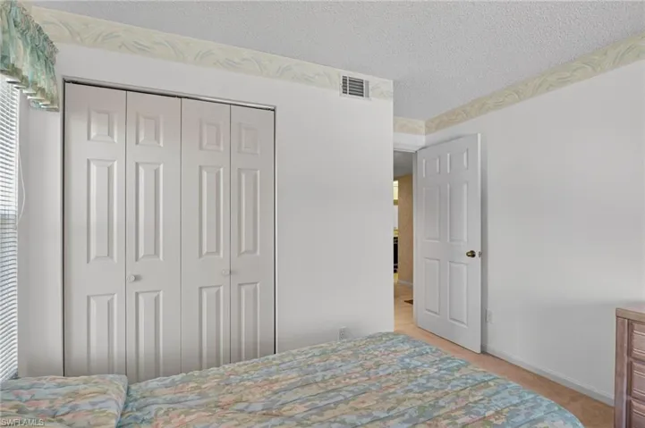 Bedroom featuring a textured ceiling, light carpet, and a closet