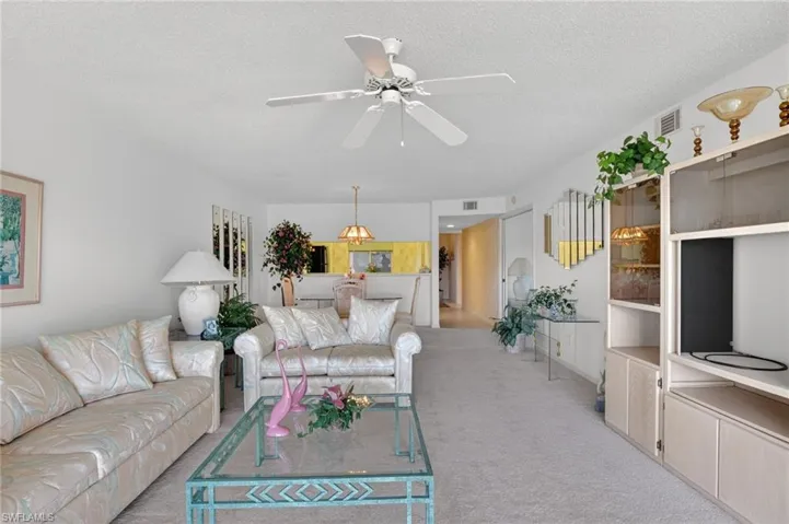 Living room featuring a ceiling fan, a textured ceiling, and light colored carpet