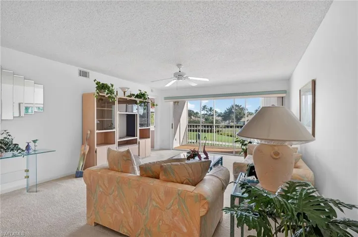 Carpeted living room featuring a textured ceiling and ceiling fan