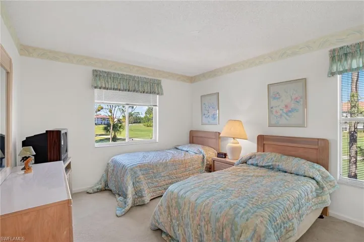 Bedroom featuring light carpet, a textured ceiling, and multiple windows