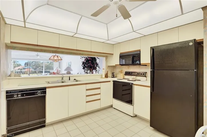Kitchen with ceiling fan, black appliances, light countertops, light tile patterned floors, and backsplash