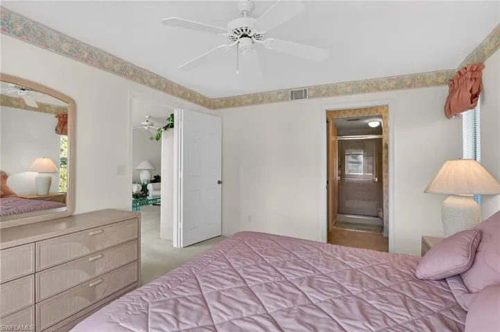 Bedroom with multiple windows, carpet flooring, ceiling fan, and connected bathroom