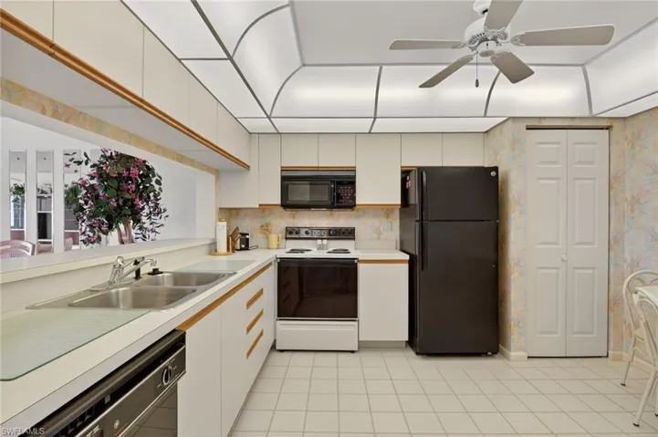 Kitchen featuring black appliances, light countertops, a ceiling fan, white cabinetry, and light tile patterned flooring