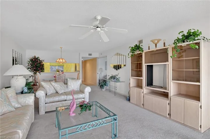 Living room with carpet flooring, a textured ceiling, and a ceiling fan