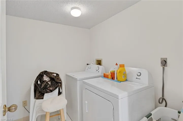 Washroom featuring a textured ceiling and washer and dryer