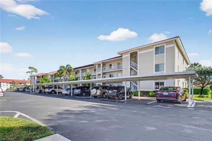 View of apartment building / complex featuring covered parking
