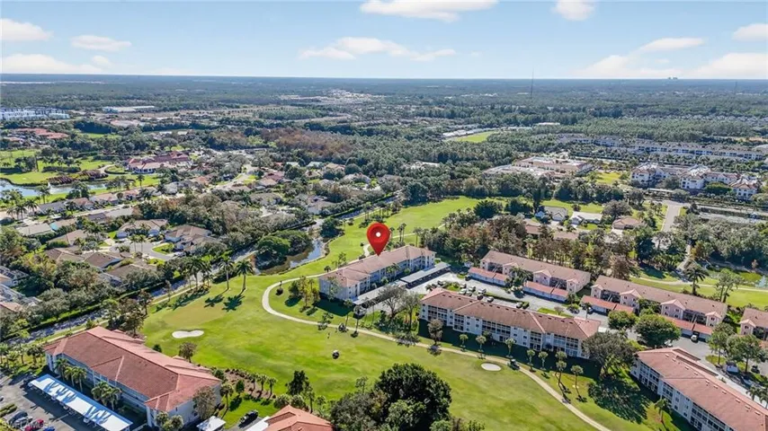 Aerial view of property's location featuring a golf club and apartment complex