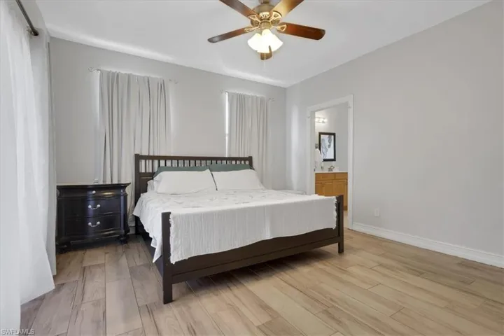 Bedroom featuring light wood-style flooring, ceiling fan, and connected bathroom