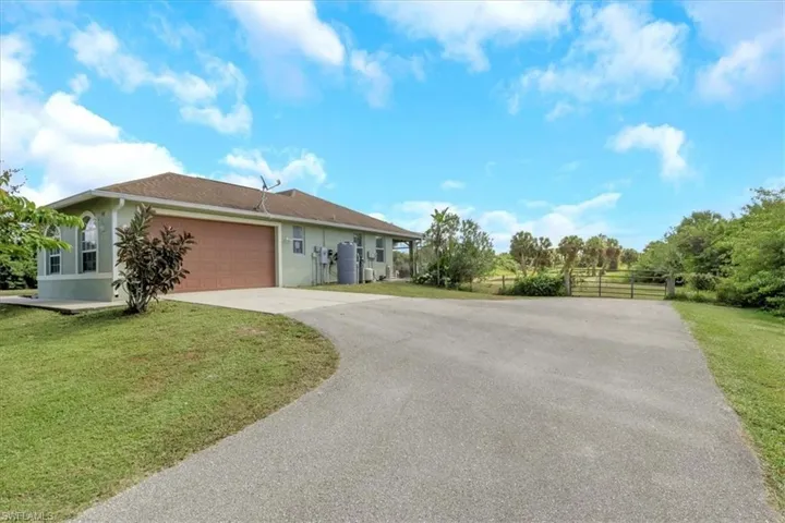 View of front facade featuring driveway, a front yard, an attached garage, and stucco siding