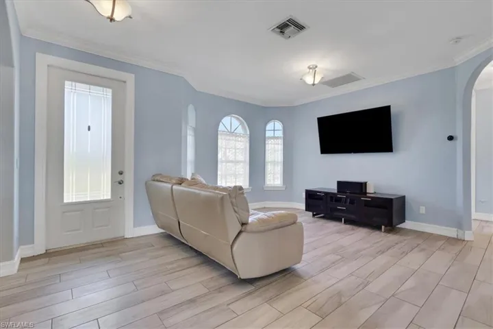 Living area featuring arched walkways, crown molding, and wood tiled floors