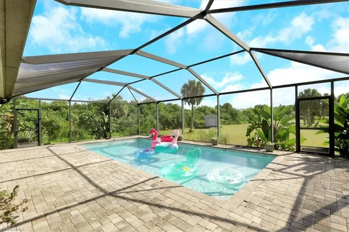 Outdoor pool featuring glass enclosure, a sunroom, and a patio