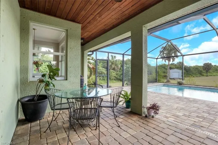 Swimming pool featuring a patio area, a sunroom, glass enclosure, a storage unit, and outdoor dining area