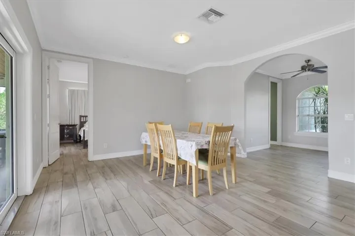 Dining area with healthy amount of natural light, arched walkways, wood finish floors, and ornamental molding