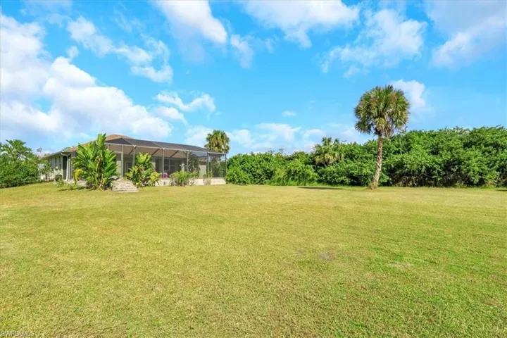 View of green lawn with a sunroom and glass enclosure