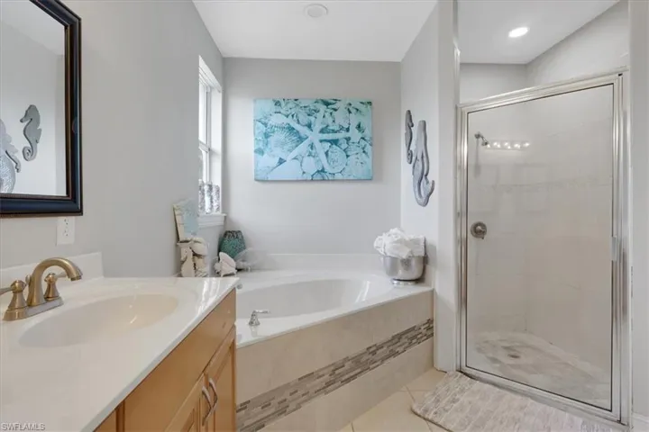 Full bathroom with vanity, a garden tub, light tile patterned floors, and a shower stall