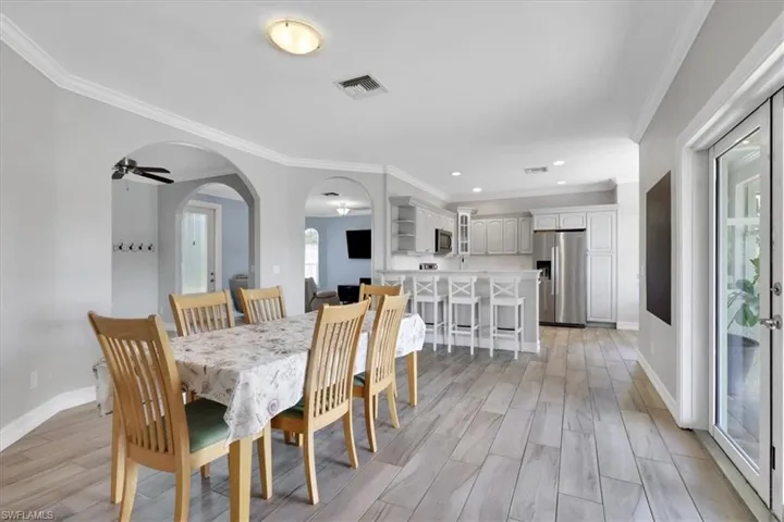 Dining area featuring wood finish floors, crown molding, a ceiling fan, arched walkways, and recessed lighting