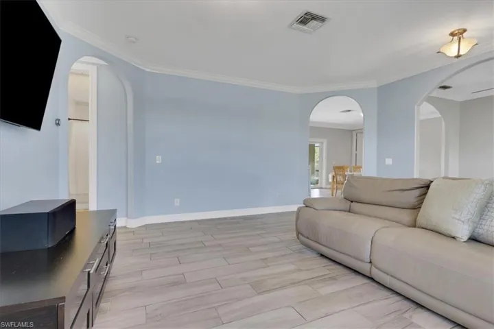 Living area with arched walkways, ornamental molding, and wood finish floors