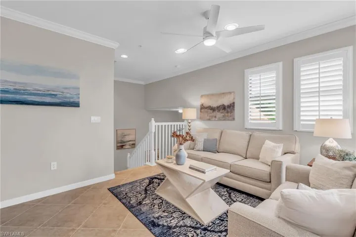 Tiled living room with ceiling fan and ornamental molding