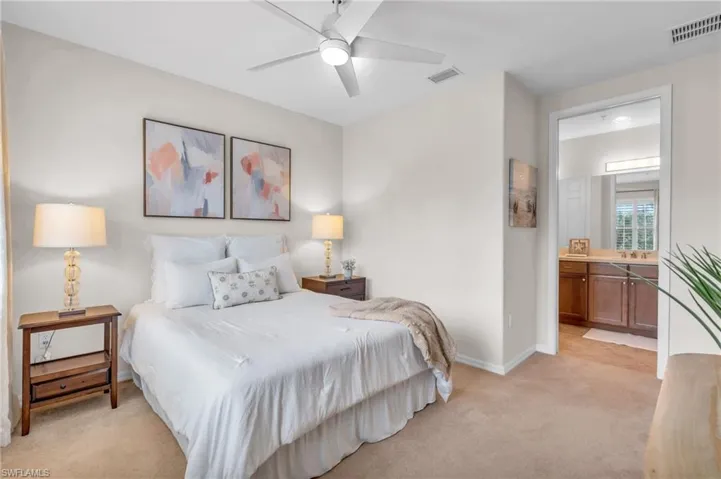 Carpeted bedroom with ensuite bathroom and ceiling fan
