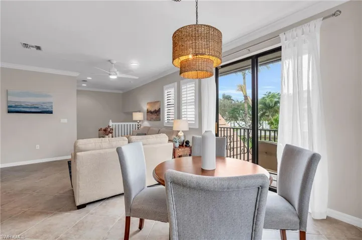 Dining area with ceiling fan with notable chandelier, light tile patterned flooring, and crown molding