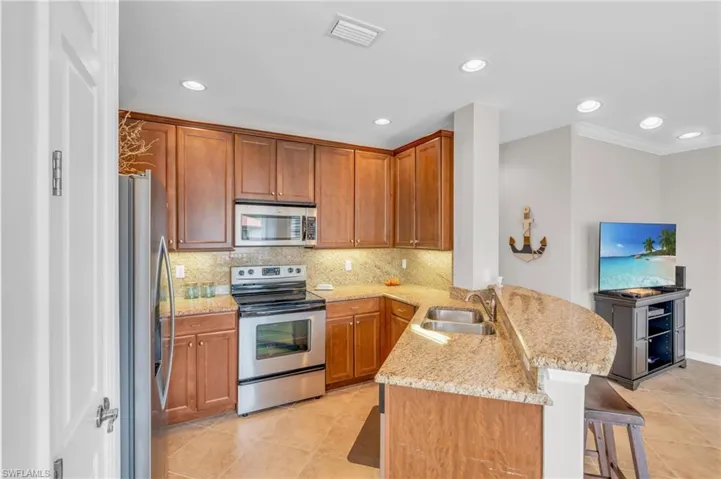 Kitchen featuring sink, stainless steel appliances, backsplash, kitchen peninsula, and a breakfast bar area