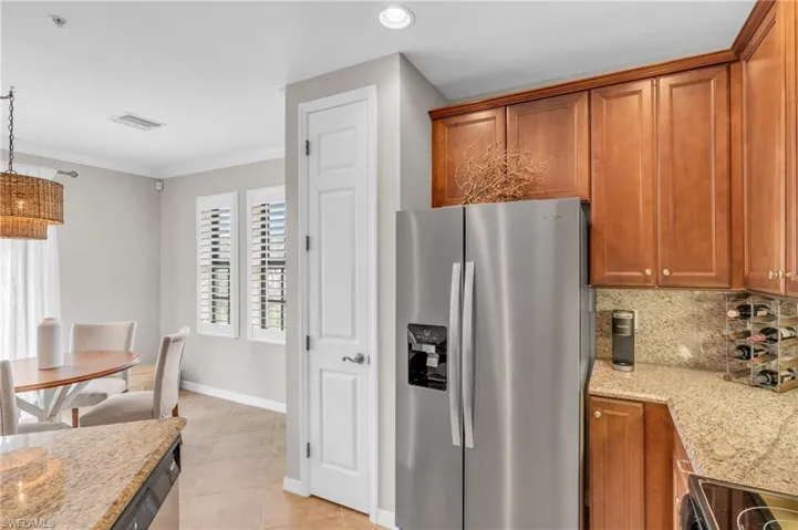 Kitchen featuring crown molding, decorative backsplash, decorative light fixtures, light stone counters, and stainless steel appliances