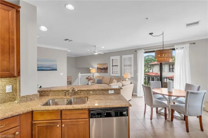 Kitchen with ceiling fan, dishwasher, light stone countertops, sink, and crown molding