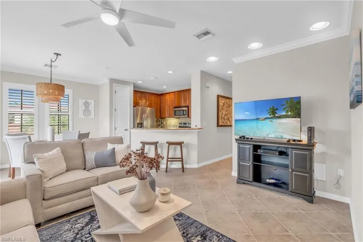 Living room featuring ceiling fan, crown molding, and light tile patterned flooring