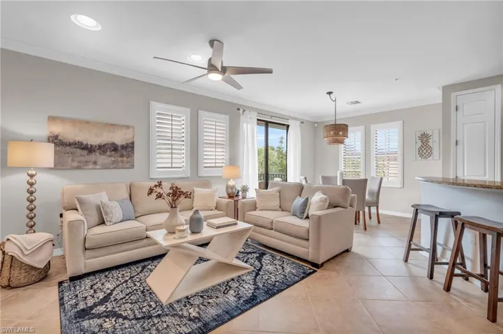 Tiled living room with ceiling fan and ornamental molding