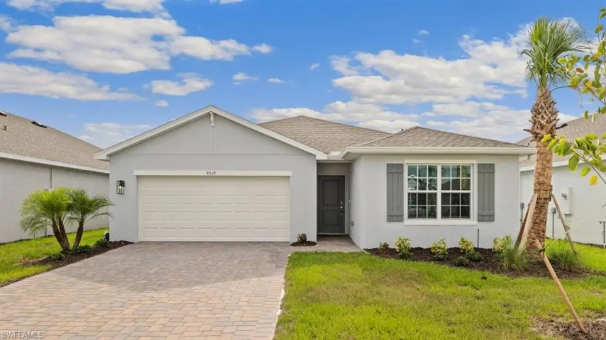 Model home. Ranch-style home featuring stucco siding, decorative driveway, a garage, a front lawn, and roof with shingles
