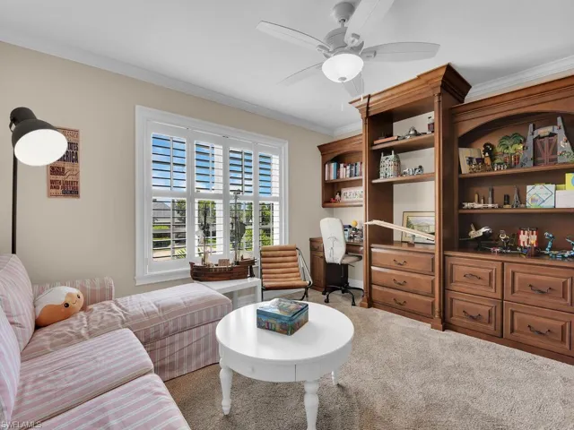 Carpeted living room featuring ceiling fan and crown molding