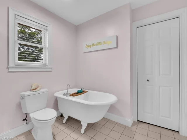 Bathroom with a tub to relax in, toilet, and tile patterned floors