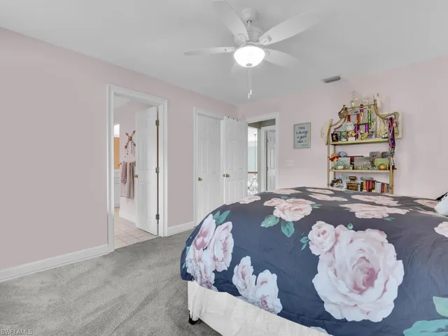 Carpeted bedroom with connected bathroom and ceiling fan