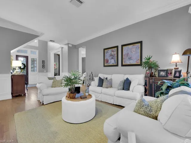 Living room featuring wood-type flooring and crown molding