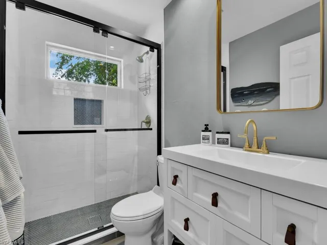 Bathroom with a shower with door, vanity, and toilet
