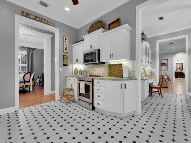 Kitchen featuring white cabinets, ceiling fan, stainless steel appliances, and crown molding