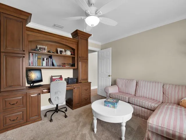 Office area featuring carpet flooring, built in desk, ceiling fan, and ornamental molding