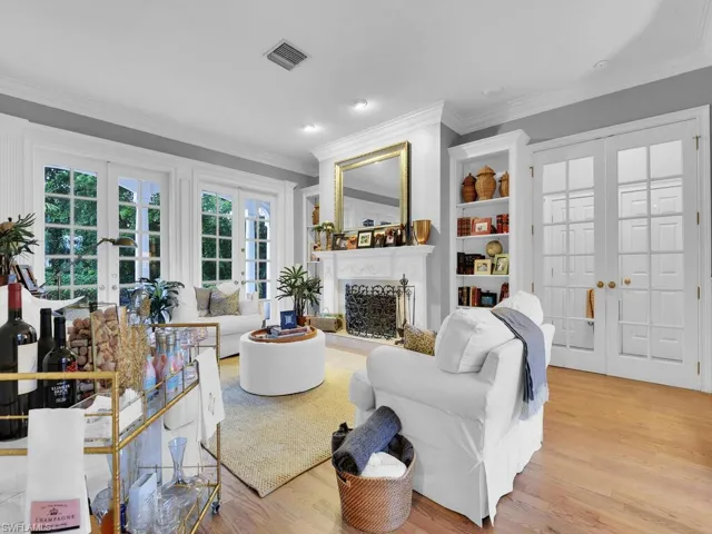 Living room with crown molding, light wood-type flooring, and french doors