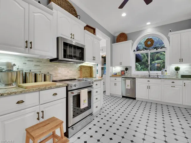 Kitchen featuring ceiling fan, ornamental molding, appliances with stainless steel finishes, and white cabinetry