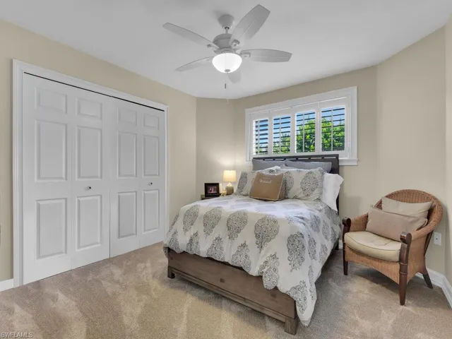 Carpeted bedroom with ceiling fan and a closet