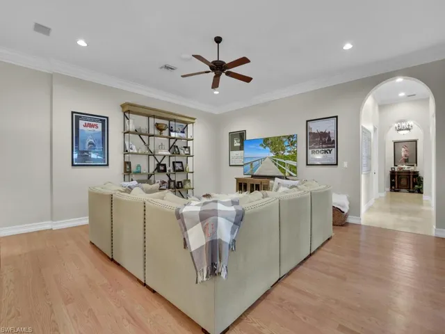 Living room featuring light wood-type flooring, ceiling fan, and ornamental molding