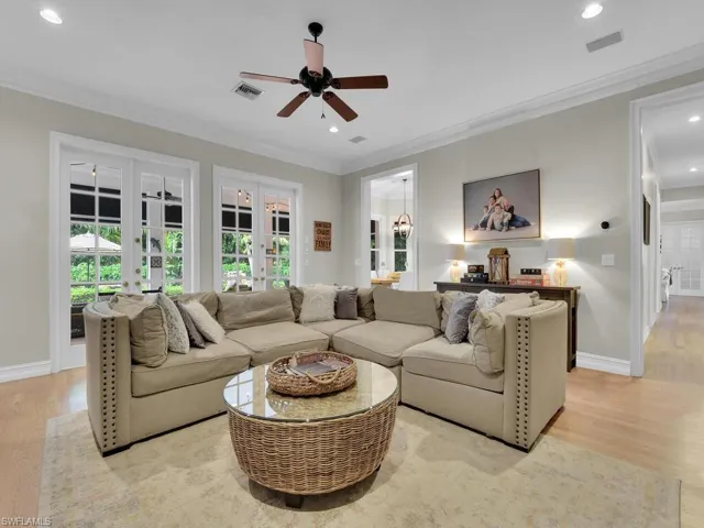 Living room featuring light hardwood / wood-style flooring, ceiling fan, ornamental molding, and french doors