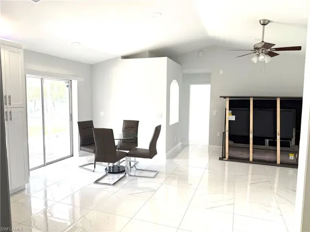 Dining area with light marble finish flooring, ceiling fan, recessed lighting, and vaulted ceiling
